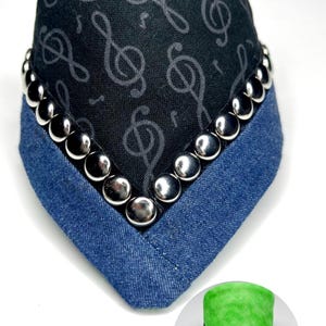 May include: Reversible dog bandana with a black and white musical note print on one side and a solid green fabric on the other side. The bandana is trimmed with silver studs.