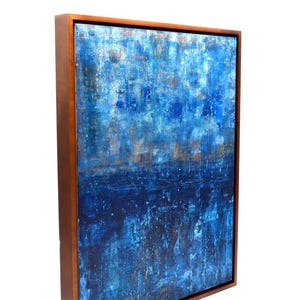 May include: Abstract painting with a blue and white color scheme. The painting is framed in a dark wood frame.