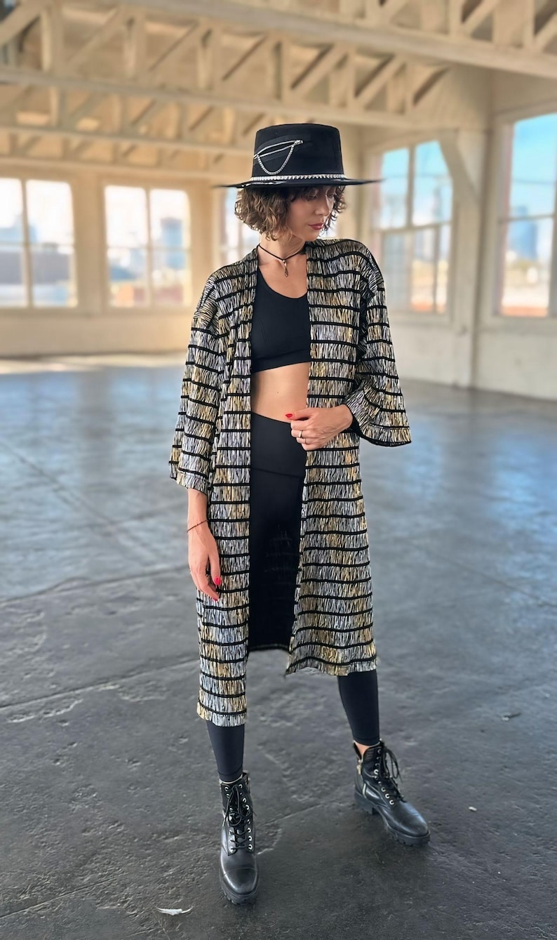 May include: A woman wearing a black and gold striped kimono with a black hat and black boots.