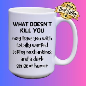 May include: A white ceramic mug featuring black text that reads: WHAT DOESN'T KILL YOU may leave you with totally warped coping mechanisms and a dark sense of humor. A gold-colored badge with the text SHOP Best Seller is attached to the handle.