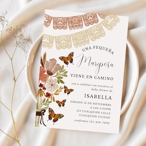 May include: A baby shower invitation with a floral design and butterflies. The invitation is for a baby girl and says "Una Pequena Mariposa Viene En Camino" which translates to "A Little Butterfly is on the Way". The invitation also includes the name Isabella, the date and time of the shower, and the address.
