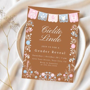 Puede incluir: Una invitación marrón para revelar el género con decoraciones florales y de pancartas. La invitación dice "Cielito Lindo" y "Join us for a Gender Reveal" con los detalles del evento. La invitación está en un plato blanco.