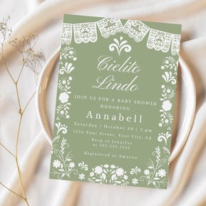 May include: Sage green baby shower invitation with white floral and lace-like decorative elements. The invitation reads "Cielito Lindo" and invites guests to honor Annabell. Includes date, time, and RSVP information.