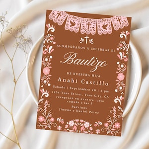 May include: A rectangular invitation card with a brown background featuring white and pink floral borders and a top banner of papel picado. The text reads: ACOMPAÑANOS A CELEBRAR EL Bautizo DE NUESTRA HIJA Anahi Castillo Sabado | Septiembre 20 | 3 pm.