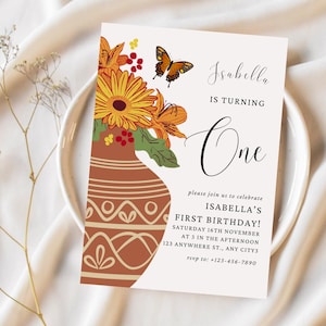 Puede incluir: Una invitación a una fiesta de primer cumpleaños con un diseño floral. La invitación presenta un jarrón con flores naranjas y amarillas, una mariposa y el texto "Isabella cumple un año".
