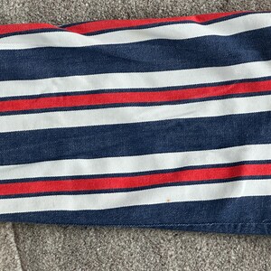 May include: Close-up of a fabric with horizontal stripes in navy blue, white, and red. The stripes are evenly spaced and run across the fabric. The fabric appears to be a medium-weight cotton or similar material.