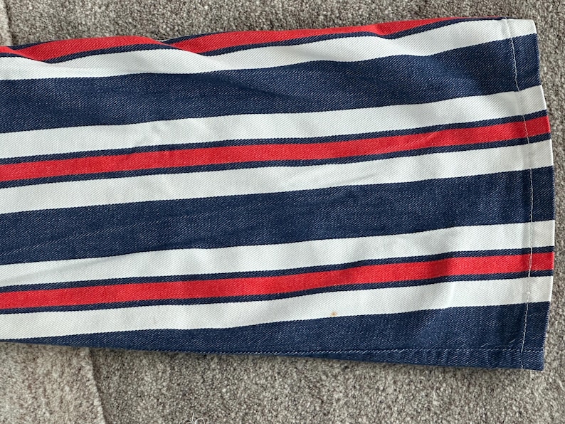 May include: Close-up of a fabric with horizontal stripes in navy blue, white, and red. The stripes are evenly spaced and run across the fabric. The fabric appears to be a medium-weight cotton or similar material.