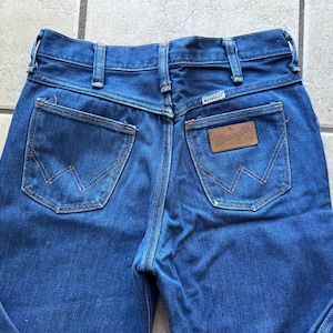 May include: A pair of blue denim jeans with a brown leather patch that says "Wrangler" on the back pocket.