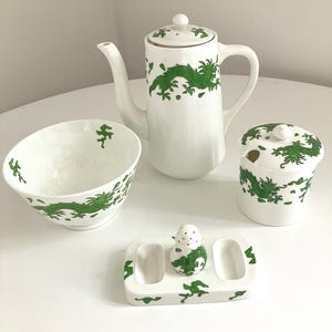 以下が含まれることがあります： 緑のドラゴン模様の白い磁器ティーセット。 ティーポット、砂糖入れ、ボウル、塩コショウ入れのセットが含まれています。 ティーポットの高さは約20cmです。