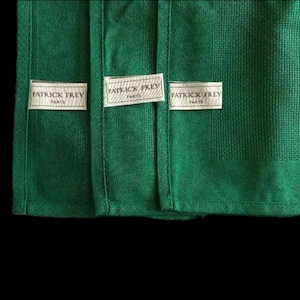 Peut inclure: Gros plan sur trois sections de tissu vert émeraude. Chaque section comporte une étiquette blanche avec le texte "PATRICK FREY PARIS". Le tissu a un aspect texturé et tissé.