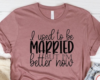 May include: A mauve t-shirt with black text that reads "I used to be married but I'm better now".