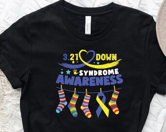 May include: Black t-shirt with a yellow and blue design that says "3.21 Down Syndrome Awareness". The design includes a heart, a handprint, a yellow ribbon, and colorful socks hanging on a clothesline.