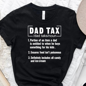 K&ouml;nnte beinhalten: Schwarzes T-Shirt mit wei&szlig;em Text, der "DAD TAX /dad taks/noun. 1. Portion of an item a dad is entitled to when he buys something for his kids. 2. Ensures food isn't poisonous 3. Definitely includes all candy and ice cream" lautet.