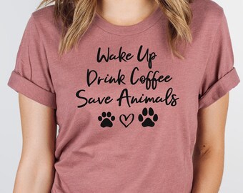 May include: A mauve t-shirt with the text "Wake Up Drink Coffee Save Animals" and two paw prints with a heart in between.