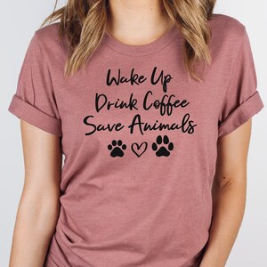 May include: A mauve t-shirt with the text "Wake Up Drink Coffee Save Animals" and two paw prints with a heart in between.