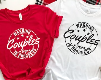 Könnte beinhalten: Zwei T-Shirts, eines rot und eines weiß, mit einer schwarz-weißen Grafik, auf der "Warning Couples Trip In Progress" steht.