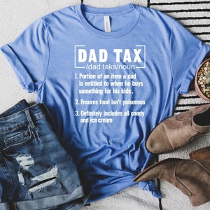 K&ouml;nnte beinhalten: Ein blaues T-Shirt mit wei&szlig;em Text, der "DAD TAX /dad taks/noun 1. Portion of an item a dad is entitled to when he buys something for his kids. 2. Ensures food isn't poisonous 3. Definitely includes all candy and ice cream" lautet.