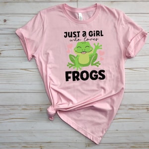 K&ouml;nnte beinhalten: Pinkes T-Shirt mit einem gr&uuml;nen Frosch-Motiv und dem Text "Just a girl who loves frogs".
