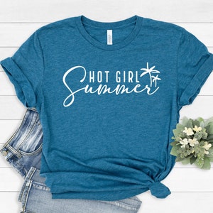 May include: A teal blue t-shirt with the text "Hot Girl Summer" in white cursive lettering and a palm tree graphic.
