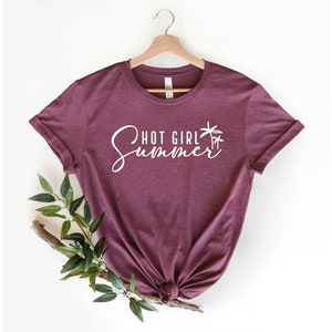 May include: A maroon t-shirt with the text "Hot Girl Summer" in white cursive lettering and a palm tree graphic.