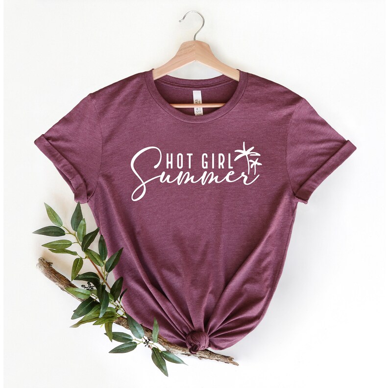 May include: A maroon t-shirt with the text "Hot Girl Summer" in white cursive lettering and a palm tree graphic.