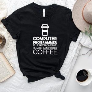 May include: Black t-shirt with white text that reads "Computer Programmer If Unresponsive Please Administer Coffee" and a white coffee cup icon.