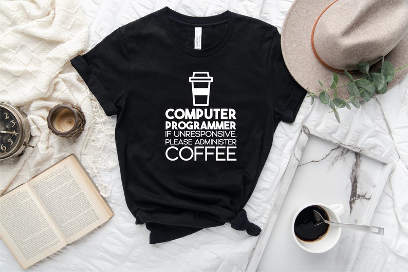 May include: Black t-shirt with white text that reads "Computer Programmer If Unresponsive Please Administer Coffee" and a white coffee cup icon.