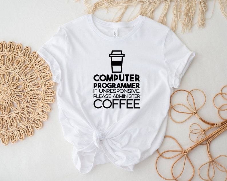 May include: White t-shirt with black text that reads "Computer Programmer. If unresponsive, please administer coffee." and a black silhouette of a coffee cup.