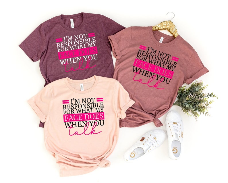 Pode incluir: Tr&ecirc;s camisetas com o mesmo design. O design diz "N&atilde;o sou respons&aacute;vel pelo que minha cara faz quando voc&ecirc; fala" em texto preto e rosa. As camisetas s&atilde;o de cores diferentes: vinho, rosa e cinza mesclado.
