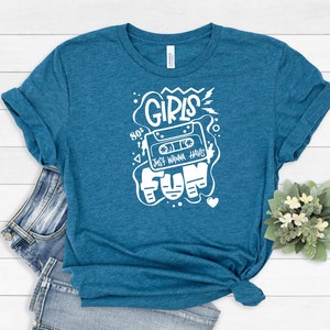 K&ouml;nnte beinhalten: Ein t&uuml;rkisfarbenes T-Shirt mit einem wei&szlig;en Grafikdesign, das ein Kassettenband mit dem Text "Girls Just Wanna Have Fun" und dem Jahr "80s" zeigt.