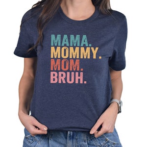 May include: A navy blue t-shirt with the text "MAMA. MOMMY. MOM. BRUH." in a retro font with colorful accents.