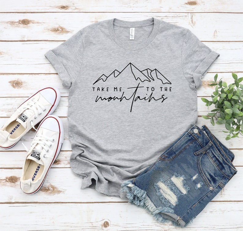 May include: Gray t-shirt with a black outline of mountains and the text "Take me to the mountains".
