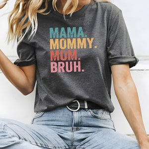 May include: A gray t-shirt with the text "MAMA. MOMMY. MOM. BRUH." printed in colorful, vintage-style lettering.