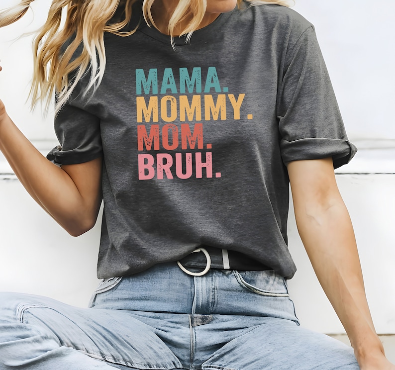 May include: A gray t-shirt with the text "MAMA. MOMMY. MOM. BRUH." printed in colorful, vintage-style lettering.