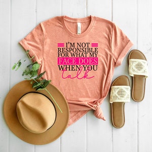 Pode incluir: Uma camiseta cor de p&ecirc;ssego com o texto "N&atilde;o sou respons&aacute;vel pelo que minha cara faz quando voc&ecirc; fala" em letras pretas e rosa.