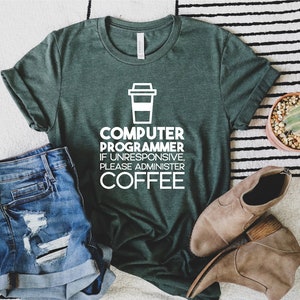 May include: A green t-shirt with a white graphic that says "Computer Programmer If Unresponsive, Please Administer Coffee" and a coffee cup icon.