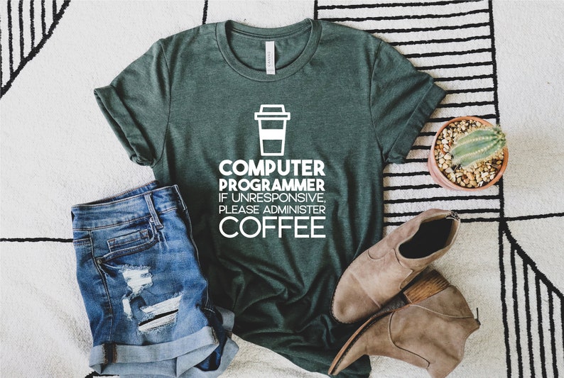 May include: A green t-shirt with a white graphic that says "Computer Programmer If Unresponsive, Please Administer Coffee" and a coffee cup icon.