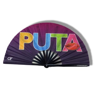 May include: A black folding fan with a purple, pink, and yellow gradient background. The word "PUTA" is printed in rainbow colors across the fan. A red lip print is on the right side of the fan.