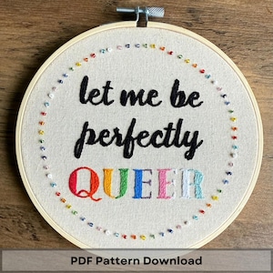 May include: A round embroidery hoop with the text "let me be perfectly QUEER" stitched in black and rainbow colors. The design is surrounded by a circle of colorful beads. The words "PDF Pattern Download" are at the bottom.