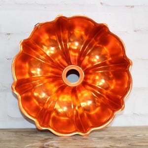 Puede incluir: Molde para pastel bundt de metal naranja con un diseño acanalado.