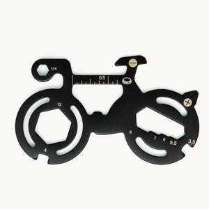 Op de afbeelding: Een zwart metalen multitool in de vorm van een fiets, voorzien van diverse uitsparingen voor moersleutels en schroevendraaiers. De tool bevat gedrukte markeringen zoals 1/4, 0,5, 12, 4, 8, 7, 6, 5,5 en 3,5, samen met iconen voor een platte en kruiskopschroevendraaier.