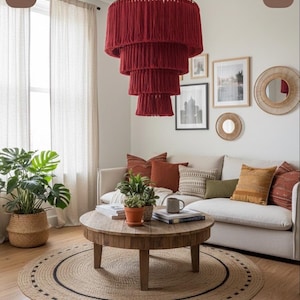 May include: A tiered chandelier featuring multiple layers of deep red fringe hanging from a circular frame. The fixture has a cascading design with each successive tier decreasing in diameter, creating a structured, layered appearance.