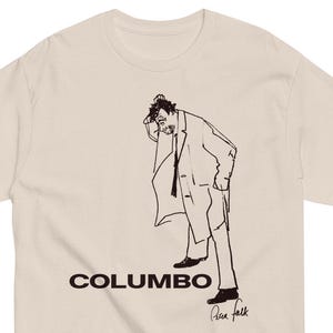 May include: A beige t-shirt with a black line drawing of a man in a suit with the word "COLUMBO" printed below the image. The signature "Peter Falk" is printed below the word "COLUMBO".