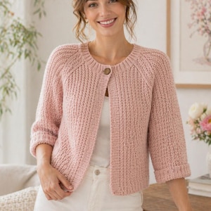Peut inclure: Un cardigan en tricot texturé rose clair avec des manches trois-quarts, une encolure ronde et un bouton marron unique sur le haut. Le vêtement est porté sur un haut blanc uni et présente un motif côtelé sur toute la surface du tissu.