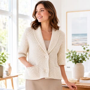 Peut inclure: Un cardigan en tricot texturé de couleur crème doté d'un col châle, de manches mi-longues et de deux poches plaquées à l'avant. Le vêtement est fermé par deux gros boutons ronds sur le devant et se porte sur un haut simple de couleur claire.