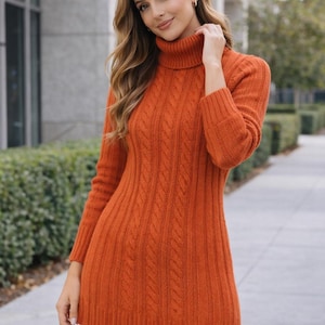 May include: A burnt orange long-sleeve sweater featuring a thick turtleneck collar and a vertical cable knit pattern. The sweater has a ribbed hem and cuffs, extending to the upper thigh, paired with solid black leggings.