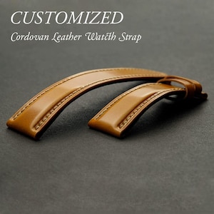May include: Two brown leather watch straps with stitching. The straps are laid out on a dark surface. The text "CUSTOMIZED Cordovan Leather Watch Strap" is above the straps.