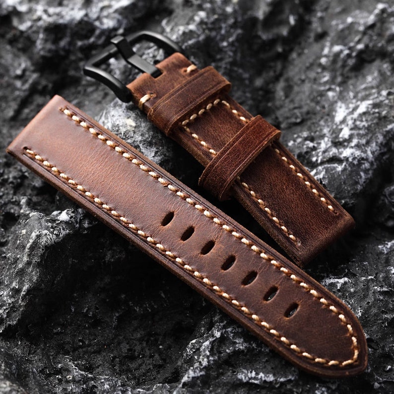 May include: Two brown leather watch straps with white stitching. One strap has a black metal buckle.