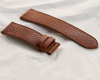 May include: Two brown leather watch straps with a textured surface. The straps are stitched with brown thread.