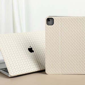 Peut inclure: Une coque en cuir tressé blanc pour iPad ou tablette. La coque a une texture subtile et un design simple.